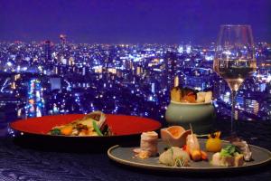 ANA Crowne Plaza Kobe, an IHG Hotel في كوبه: طاولة مع طبقين من الطعام وكأس من النبيذ