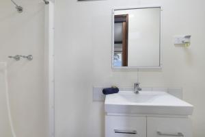 a white bathroom with a sink and a mirror at Paradise Palms Caravan Park in Rathmines