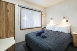 a hotel room with a bed with a blue blanket at Paradise Palms Caravan Park in Rathmines