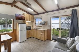 a kitchen with a refrigerator and a table and a couch at Paradise Palms Caravan Park in Rathmines