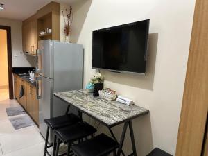 a kitchen with a table with a television on a wall at Kathys Crib at Shell Residences in Manila