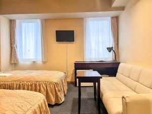 a hotel room with two beds and a couch and a television at Hotel Sho Sapporo in Sapporo