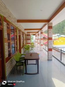 Zimmer mit einem Tisch und Stühlen auf einem Balkon in der Unterkunft Chojh Inn Guest House in Kasol