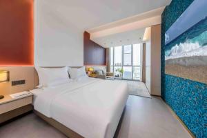 un grande letto bianco in una stanza con un grande dipinto di Kunming Yuxi Hotel a Kunming