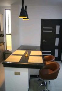 a kitchen with a counter with two stools and a table at Sky Blue Apartments in Manta