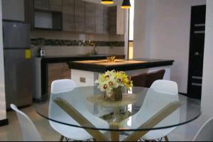 a glass table with white chairs and a vase of flowers at Sky Blue Apartments in Manta