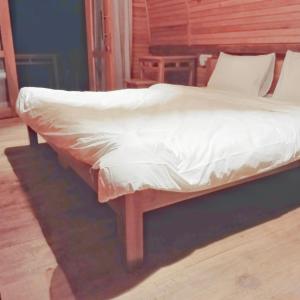 a bed with white sheets on a wooden bed frame at Bunaken 18 Oceanfront Boutique Lodge in Bunaken