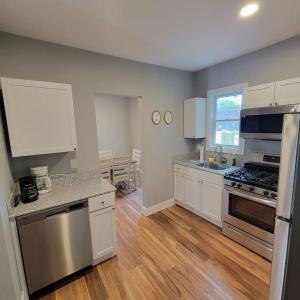 a kitchen with white cabinets and a wooden floor at Beautiful Renovated 4 Bedroom. Walk to Niagara Falls. in Niagara Falls