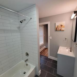a bathroom with a white tub and a sink at Beautiful Renovated 4 Bedroom. Walk to Niagara Falls. in Niagara Falls