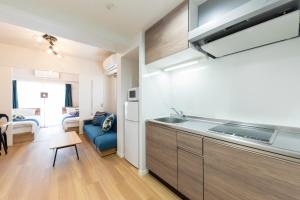 a kitchen with a sink and a couch in a room at SG RESIDENCE INN HAKATA in Fukuoka