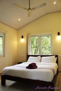 a bedroom with a large white bed with two windows at Lavender Plantation Stay vagamon in Vagamon