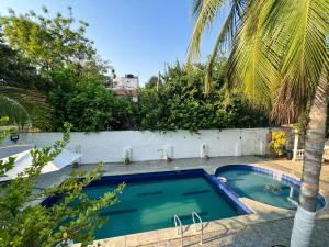 una piscina en un patio con una palmera en Casa campestre con piscina cerca al aeropuerto y la playa en Santa Marta