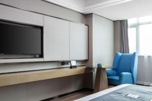 Habitación de hotel con TV y silla azul en Echarm Hotel Haikou en Haikou