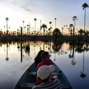 two people in a boat on a lake with palm trees at River Point Hostel in Puerto Maldonado