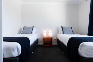 duas camas individuais num quarto com mesa de cabeceira em Homely Hideaway with Parking & WiFi em Alanvale