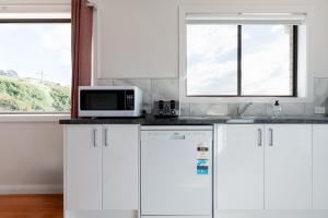 uma cozinha branca com armários brancos e um micro-ondas em Homely Hideaway with Parking & WiFi em Alanvale