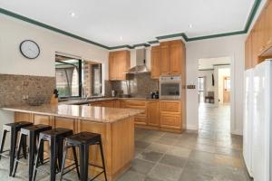 a kitchen with wooden cabinets and a large island with bar stools at Villa Di Morcone By The Bay in Rye