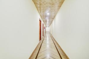 einen langen Korridor in einem Gebäude mit einer weißen Wand in der Unterkunft Vishwakarma Palace in Neu-Delhi