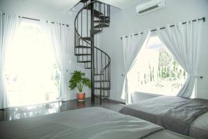 a bedroom with a spiral staircase in front of a window at Evergreen Tree Homestay in Phan Thiet