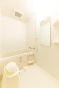 a white bathroom with a toilet and a mirror at SG Residence Inn Hakataekiminami in Fukuoka