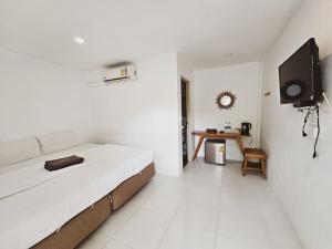 ein weißes Zimmer mit einem Bett und einem Fernseher in der Unterkunft BB Hidden House in Ko Phi Phi