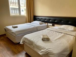 2 Betten in einem Hotelzimmer mit Fenster in der Unterkunft Syaz Meridien Hotel in Malakka
