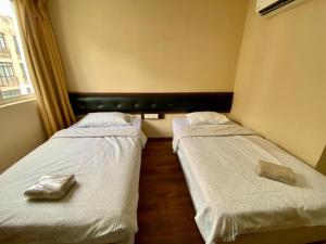 2 camas en una habitación pequeña con sábanas blancas en Syaz Meridien Hotel, en Melaka