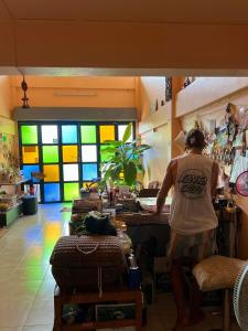 a man standing at a table in a room with colorful windows at Karma Home Hostel in Phitsanulok