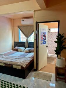 a bedroom with a bed and a door to a bathroom at Karma Home Hostel in Phitsanulok