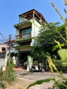 a building with two motorcycles parked in front of it at Karma Home Hostel in Phitsanulok