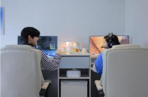 dwoje ludzi siedzących przy biurku w biurze w obiekcie Aank Air Hotel Daejeon w mieście Geochang