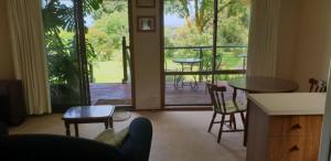 sala de estar con mesa y sillas y balcón en Ripplebrook Country Cottage, en Foster