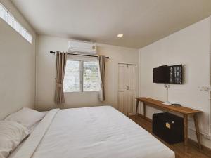 a bedroom with a white bed and a television at Casa Maya House in Phi Phi Islands
