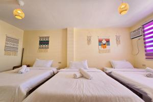 3 camas en una habitación con sábanas blancas en Surfside Hostel, en San Juan