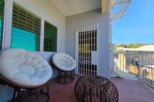 a porch with two white chairs and a balcony at Surfside Hostel LU Surf Town in San Juan