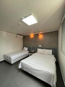 two beds in a room with white sheets at Motel Choo Eok in Sokcho