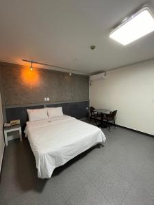 a bedroom with a large white bed and a table at Motel Choo Eok in Sokcho