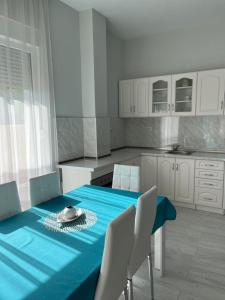 een keuken met een blauwe tafel en witte kasten bij Вила in Asprovalta