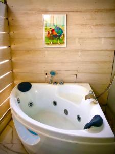 V20 Boutique Jacuzzi Hotel - SHA Extra Plus في بانكوك: حوض استحمام في حمام مع لوحة على الحائط