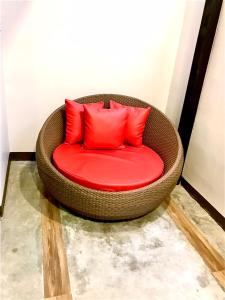 - Silla de mimbre con almohadas rojas en la habitación en V20 Boutique Jacuzzi Hotel - SHA Extra Plus en Bangkok