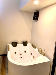 V20 Boutique Jacuzzi Hotel - SHA Extra Plus في بانكوك: حوض استحمام أبيض في حمام به حنفيات ذهب