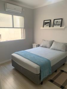 ein weißes Schlafzimmer mit einem Bett mit einer blauen Decke in der Unterkunft Apartamento em Santos na Ponta da Praia in Santos