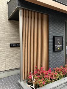 una puerta delantera de un edificio con flores en Hotel Ninestates Kagoshima, en Kagoshima