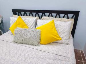 uma cama com almofadas amarelas e brancas em CamiStays Homestay in Camiguin, Best for Groups or Family em Mambajao