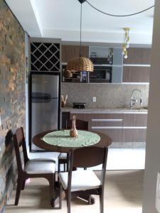 cocina con mesa, sillas y nevera en Apartamento na Serra Gaúcha en Caxias do Sul