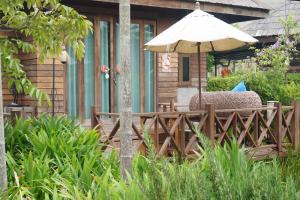 um pátio com um guarda-sol e cadeiras sobre uma cerca em Tongna Cottage Natural Resort em Chiang Mai