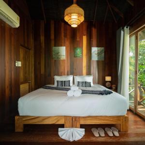 a bedroom with a large bed with a wooden wall at Tongna Cottage Natural Resort in Chiang Mai