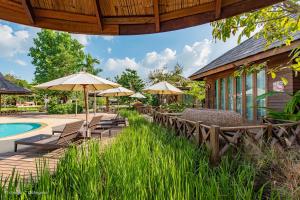 un patio con sillas y sombrillas junto a una piscina en Tongna Cottage Natural Resort en Chiang Mai