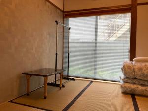 um quarto com uma mesa e uma grande janela em ゲストハウスみんちゅう 