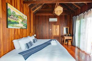a bedroom with a large white bed with wooden walls at Tongna Cottage Natural Resort in Chiang Mai